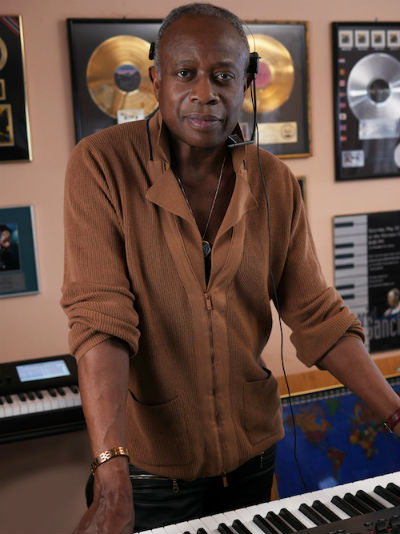 David Sancious standing at keyboard with albums in the background